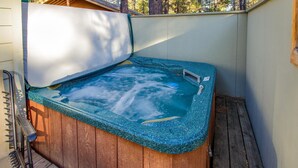 A hot tub with a wooden deck and a metal ladder.
