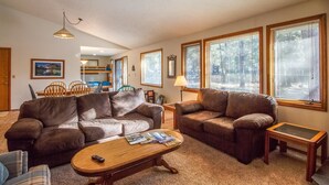 A spacious living room with two brown leather sofas, a wooden coffee table, and a dining area with a table and chairs.