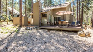 A cabin with a deck, outdoor seating, and a large umbrella. - Leisure 5 (Bend)