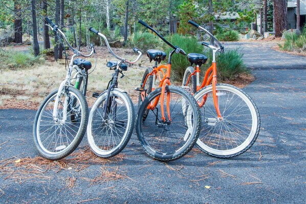 Three bicycles parked on a paved path with trees and a building in the background.