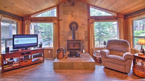 A cozy living room with a stone fireplace, a television, and a comfortable armchair. - Lynx 5 (Bend)