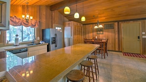 A kitchen with a large island, wooden cabinets, and pendant lighting. - Lynx 5 (Bend)