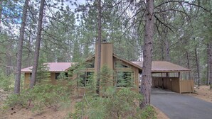 A cabin with a metal roof, surrounded by pine trees. - Lynx 5 (Bend)