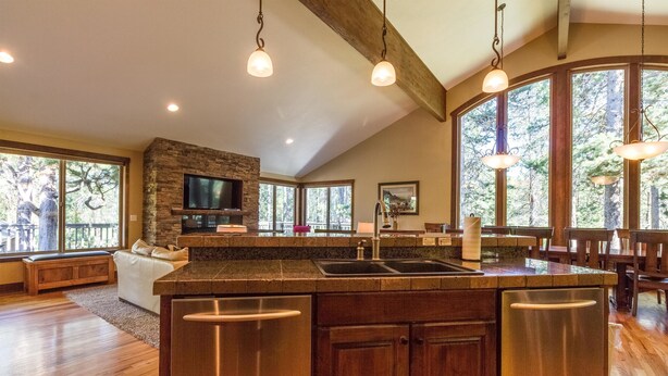 A spacious kitchen with a large island, wooden cabinets, and a stone accent wall. - Malheur 5 (Bend)