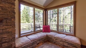 A corner seating area with stone walls and large windows overlooking a deck. - Malheur 5 (Bend)