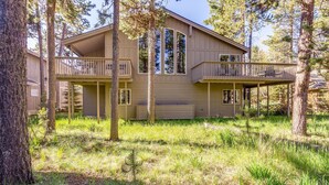 A two-story cabin with a balcony on the upper floor, surrounded by trees. - Malheur 5 (Bend)