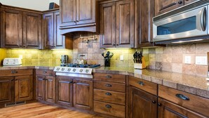 A kitchen with wooden cabinets, a gas stove, and a microwave. - Malheur 5 (Bend)
