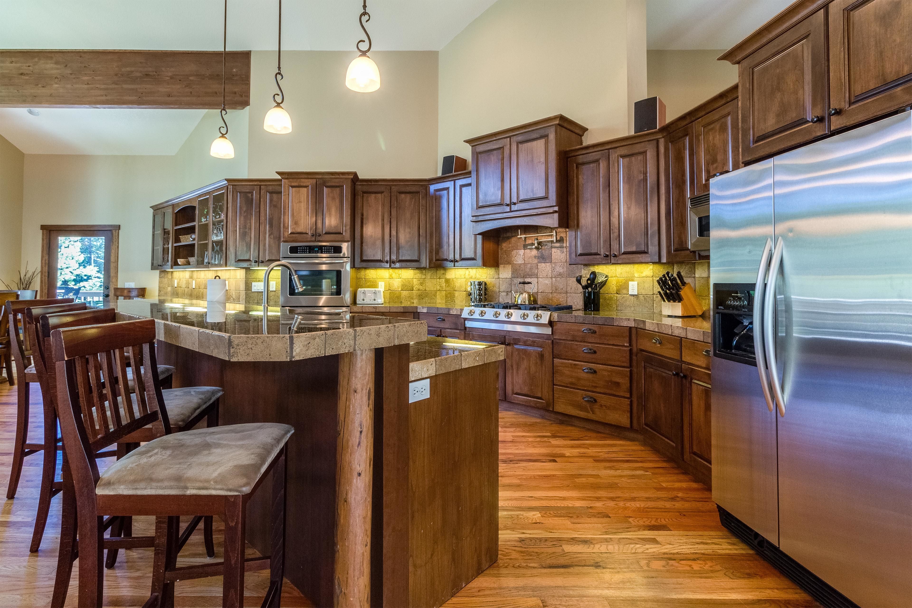 A spacious kitchen with wooden cabinets, a stainless steel refrigerator, and a central island with bar stools.