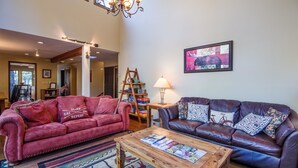 A spacious living room with two leather sofas, a wooden coffee table, and a chandelier. - Sparks 5 (Bend)