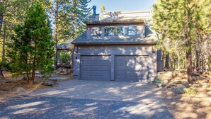A two-story building with a garage, surrounded by trees and a paved driveway. - Sparks 5 (Bend)