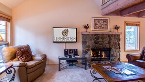 Un salon chaleureux avec une cheminée en pierre, des meubles en cuir et un panneau encadré portant le nom de Bennington Properties.