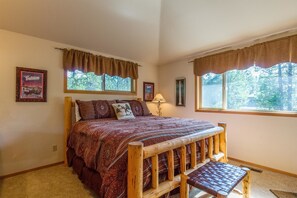 A bedroom with a large bed, a wooden bench, two windows with curtains, and framed pictures on the wall. - Mt Rose 2 (Bend)
