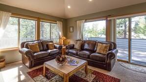 A living room with two leather sofas, a wooden coffee table, and large windows with curtains. - Mt Rose 2 (Bend)