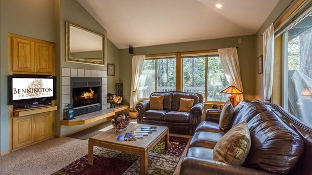 A cozy living room with a fireplace, leather sofas, a coffee table, and a television. - Mt Rose 2 (Bend)