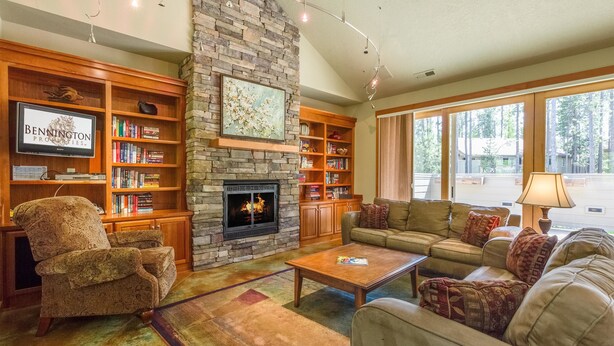 A cozy living room with a stone fireplace, wooden bookshelves, a comfortable sofa, and a television. - Mt Rose 9 (Bend)