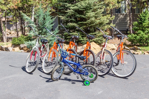 A row of bicycles parked in a parking lot with trees and a building in the background.