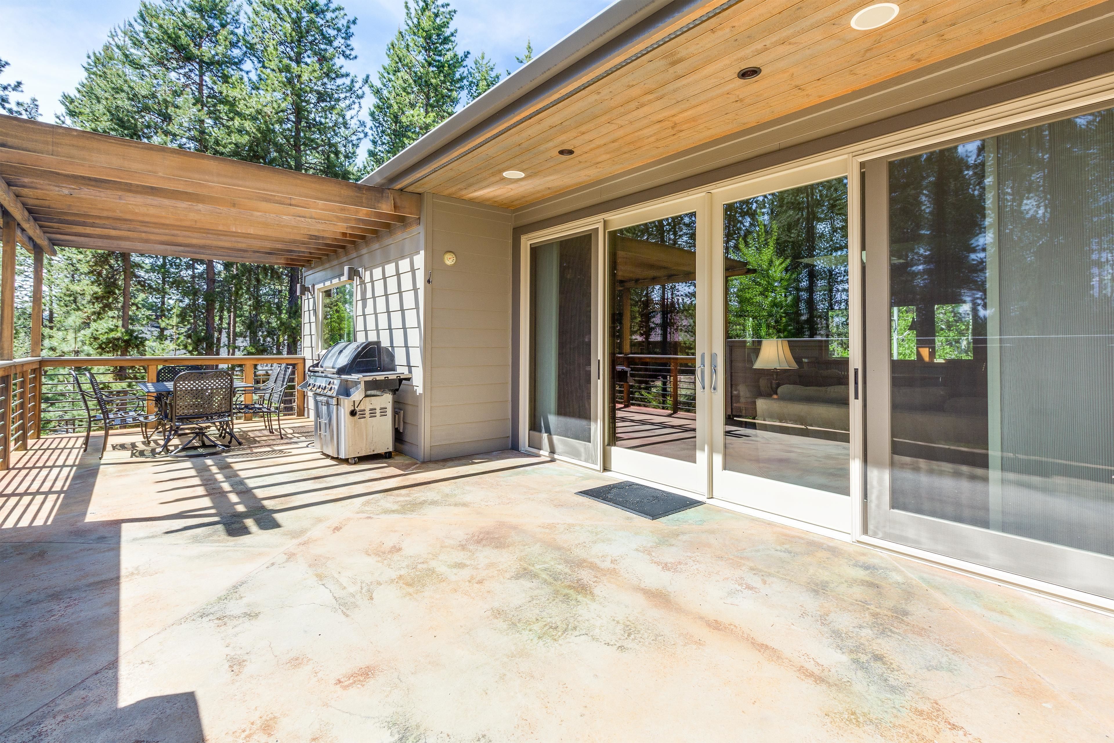 A covered patio area with a grill, outdoor furniture, and a sliding glass door leading to an outdoor seating area.
