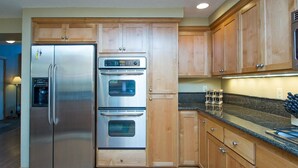 Una cocina con armarios de madera, un refrigerador de acero inoxidable y un horno empotrado.