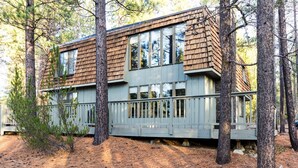 Una cabaña con fachada de madera, ventanas amplias y una terraza.