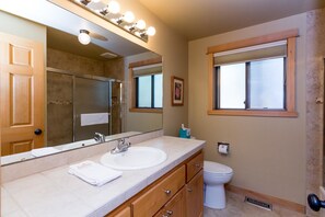 A bathroom with a large mirror, vanity with a sink, and a toilet. - Muskrat 4 (Bend)
