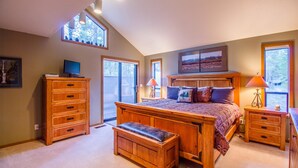 A bedroom with a large bed, wooden dresser, and a television on a stand. - Nine Iron 10 (Bend)