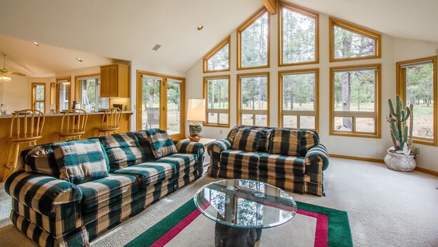 Un salón amplio con ventanas grandes, una chimenea y una zona de comedor con muebles de madera.