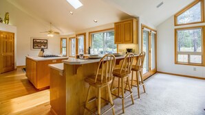 Una cocina amplia con armarios de madera, una isla central con taburetes de bar, ventanas grandes y un tragaluz.