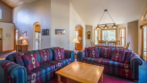 Ein Wohnzimmer mit zwei Sofas, einem Holztisch und einem Essbereich mit Tisch und Stühlen.