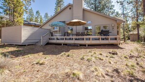 Eine Hütte mit einer Terrasse, Sitzgelegenheiten im Freien und einem Grillbereich.