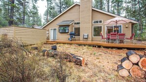 A cabin with a deck, outdoor seating, and a grill area.