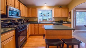 A kitchen with wooden cabinets, a stainless steel microwave, a stove, and a sink.