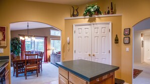 A kitchen with wooden cabinets, a granite countertop, and a dining area with a wooden table and chairs.