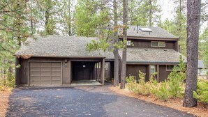 A two-story house with a garage, surrounded by trees and a driveway. - Elk Lane 7 (Bend)