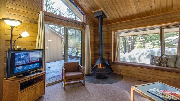 A cozy cabin interior with a fireplace, a television, and a comfortable seating area.