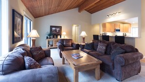 A spacious living room with leather sofas, a wooden coffee table, and a kitchen in the background. - Pioneer 7 (Bend)