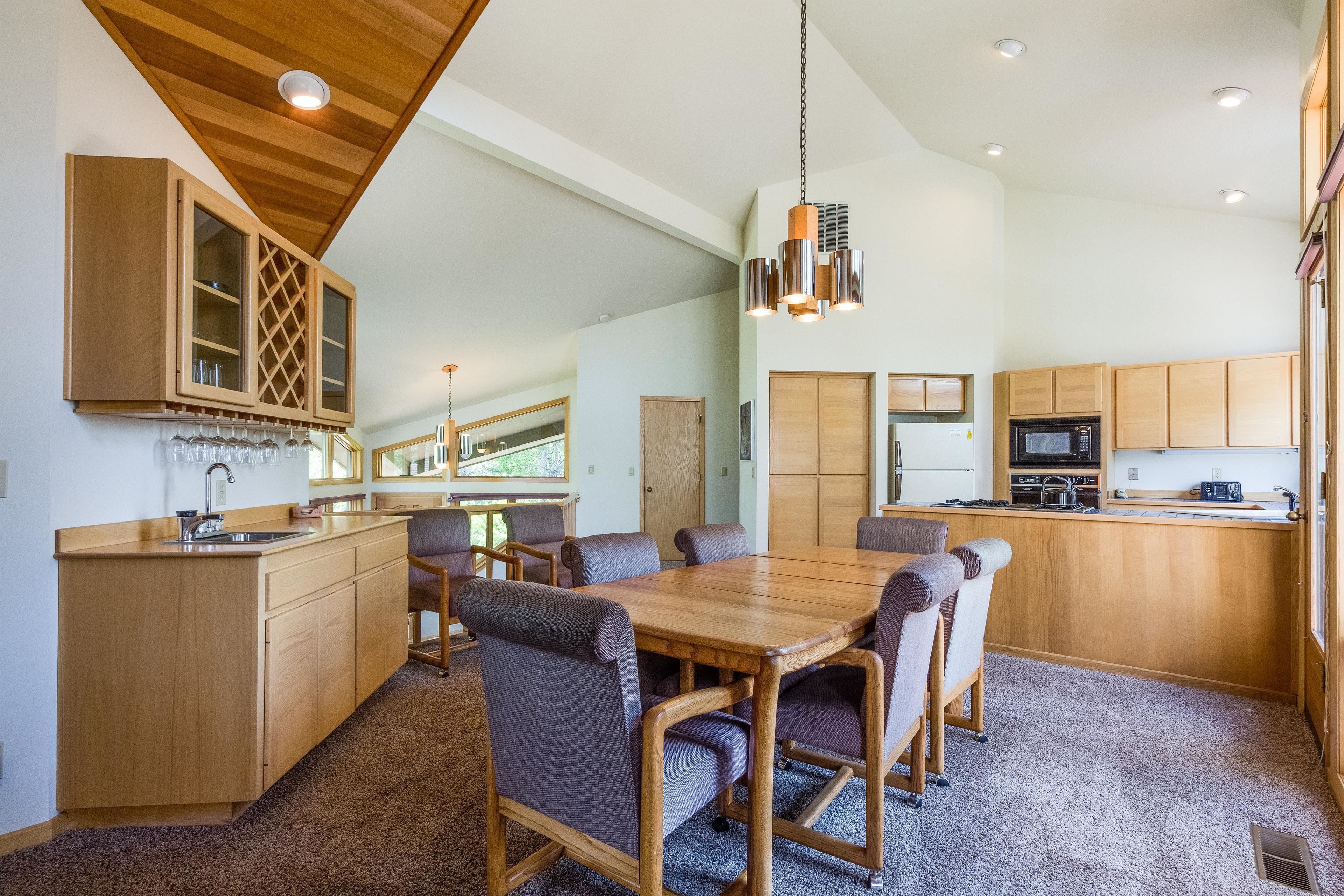A spacious kitchen with wooden cabinets, a central island with a sink, and a dining area with a large table and chairs.