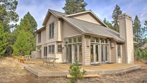Une maison à deux étages dotée d’une terrasse, de grandes fenêtres et d’une cheminée.