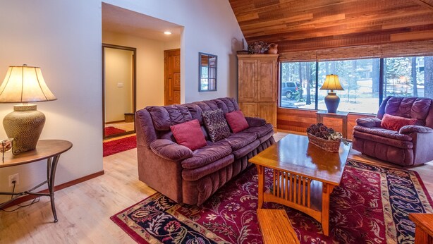 Un salon chaleureux avec un canapé moelleux de couleur violette, une table basse en bois et une grande fenêtre donnant sur le paysage extérieur.