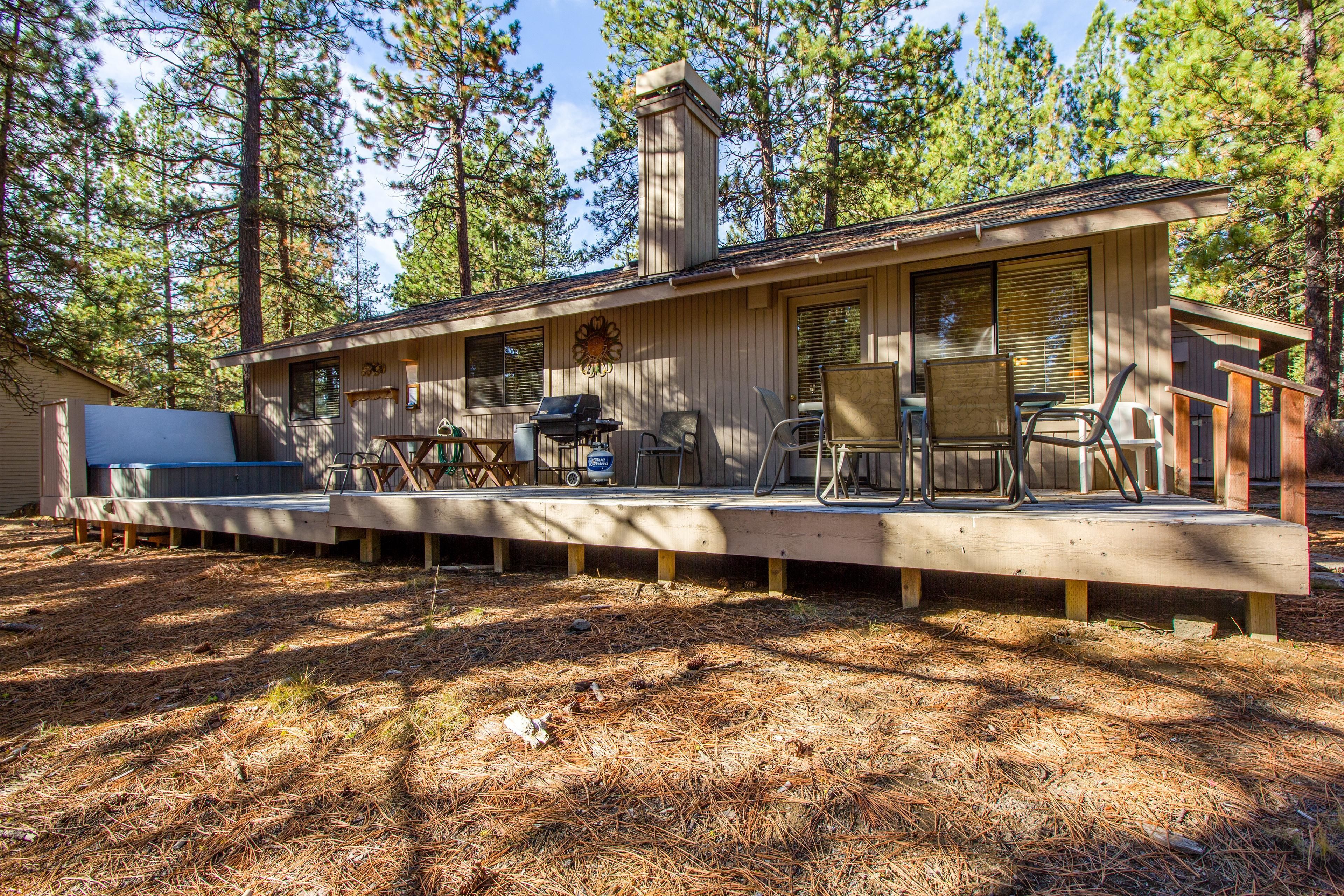 A cabin with a deck, outdoor seating, and a grill area.