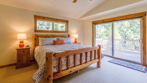 Ein Schlafzimmer mit einem Holzbett, zwei Nachttischlampen, einem Deckenventilator und einer großen Schiebeglasdoor zum Balkon.