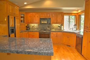 A kitchen with wooden cabinets, granite countertops, a stove, and a sink. - Quelah Lane 20 (Bend)