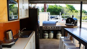 A compact kitchen with a gas stove, a coffee maker, and a refrigerator. - Down Under Hostels on Harriet (Darwin)