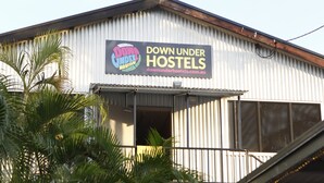 A building with a sign that reads "DOWN UNDER HOSTELS" and a website address. - Down Under Hostels on Harriet (Darwin)