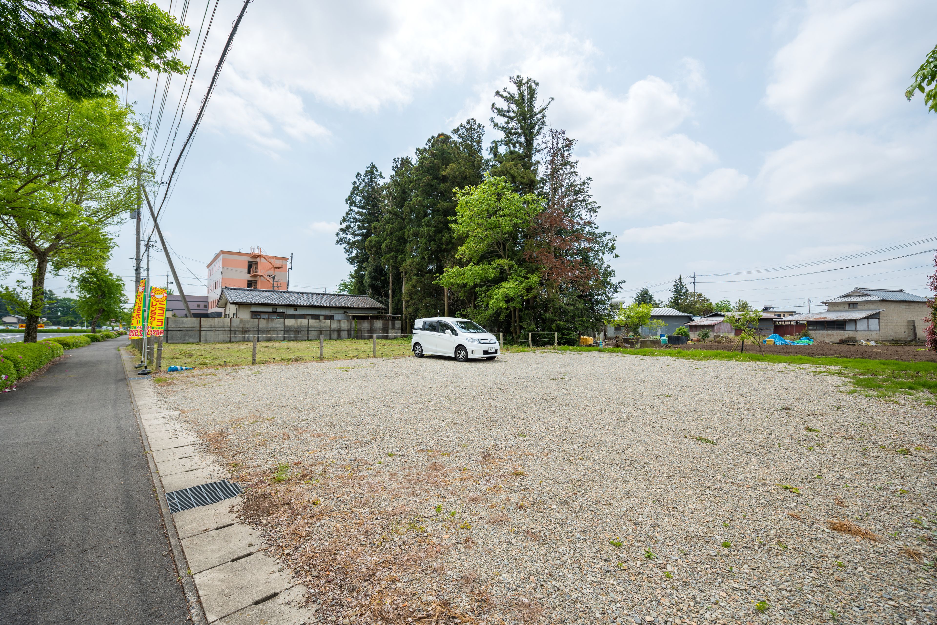 A gravel parking area with a white van parked in the center.