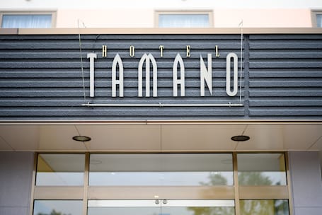 A hotel sign with the name "HOTEL TAMANO" in large, white letters on a dark background.