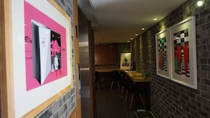 Un couloir avec un comptoir d’accueil, un guichet et des œuvres d’art encadrées accrochées aux murs.