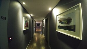 A hallway with framed artwork on the walls, a number '503' on the left, and a door at the end. - Hotel Tong Yeondong Jeju (Jeju City)
