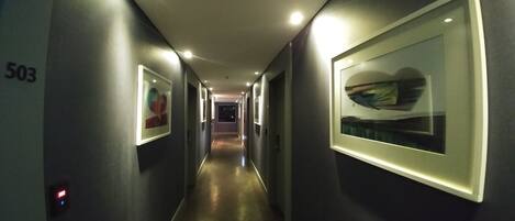 A hallway with framed artwork on the walls, a number '503' on the left, and a door at the end.