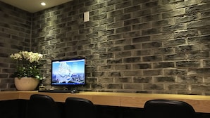 A reception area with a stone wall, a monitor displaying a map, and a potted plant. - Hotel Tong Yeondong Jeju (Jeju City)