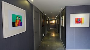 Un couloir aux murs ornés d’œuvres d’art encadrées, doté d’un plancher poli et d’un plafond au design moderne.